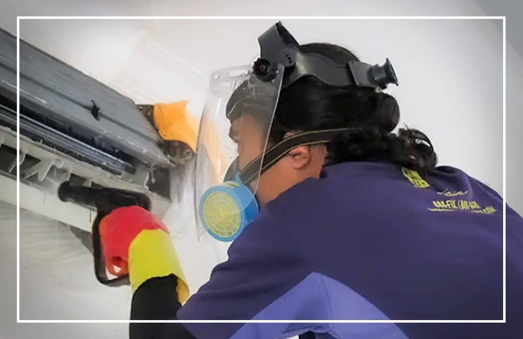 Technician with gloves and a hard hat using equipment on a grey wall